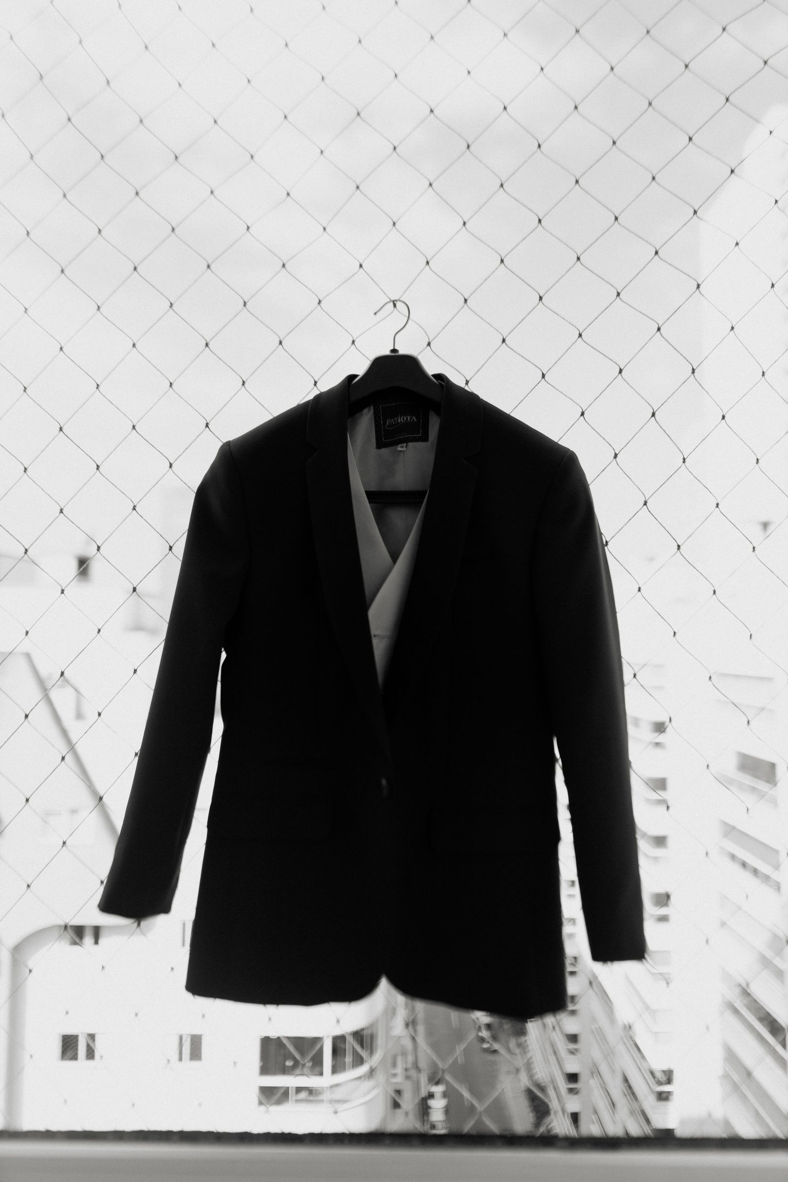 A black suit jacket on a hanger by a window in low evening light