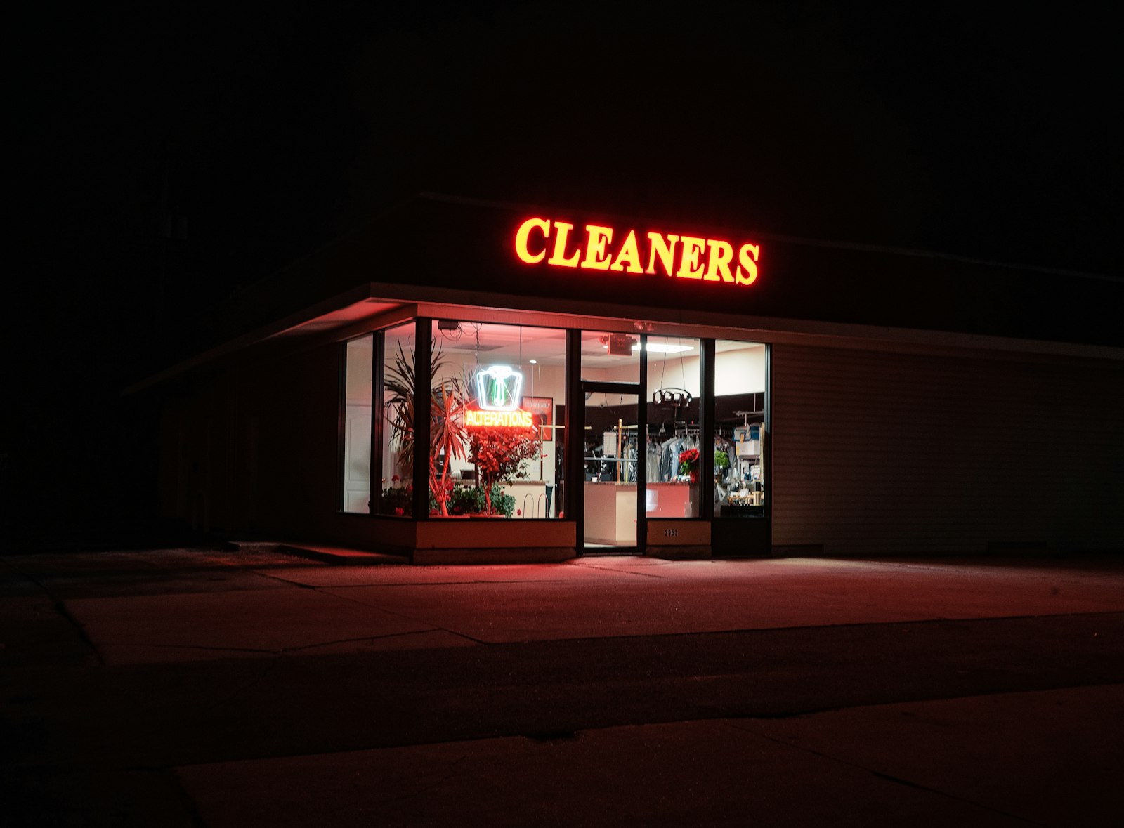 A cleaners storefront glowing after dark