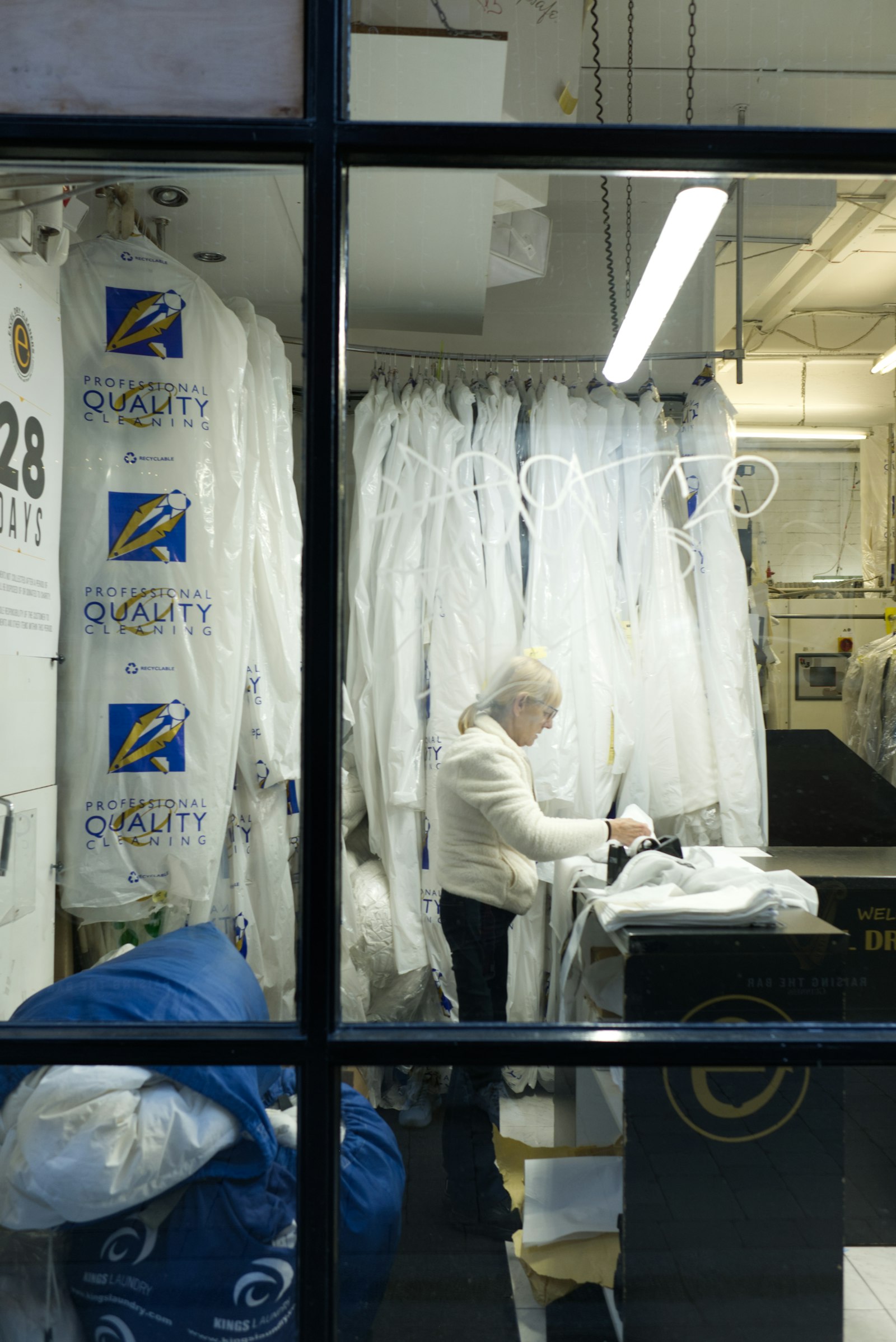A cleaner inspects garments hanging at the sorting rail