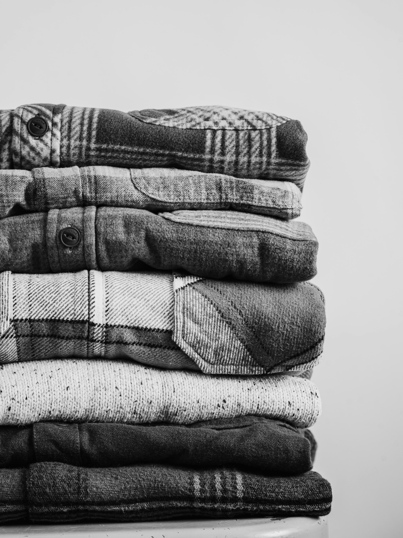 A stack of folded shirts, photographed in black and white