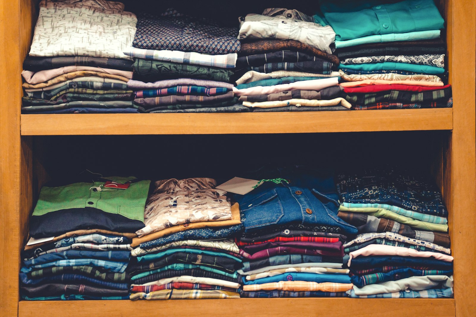 Folded shirts stacked square on a wooden shelf