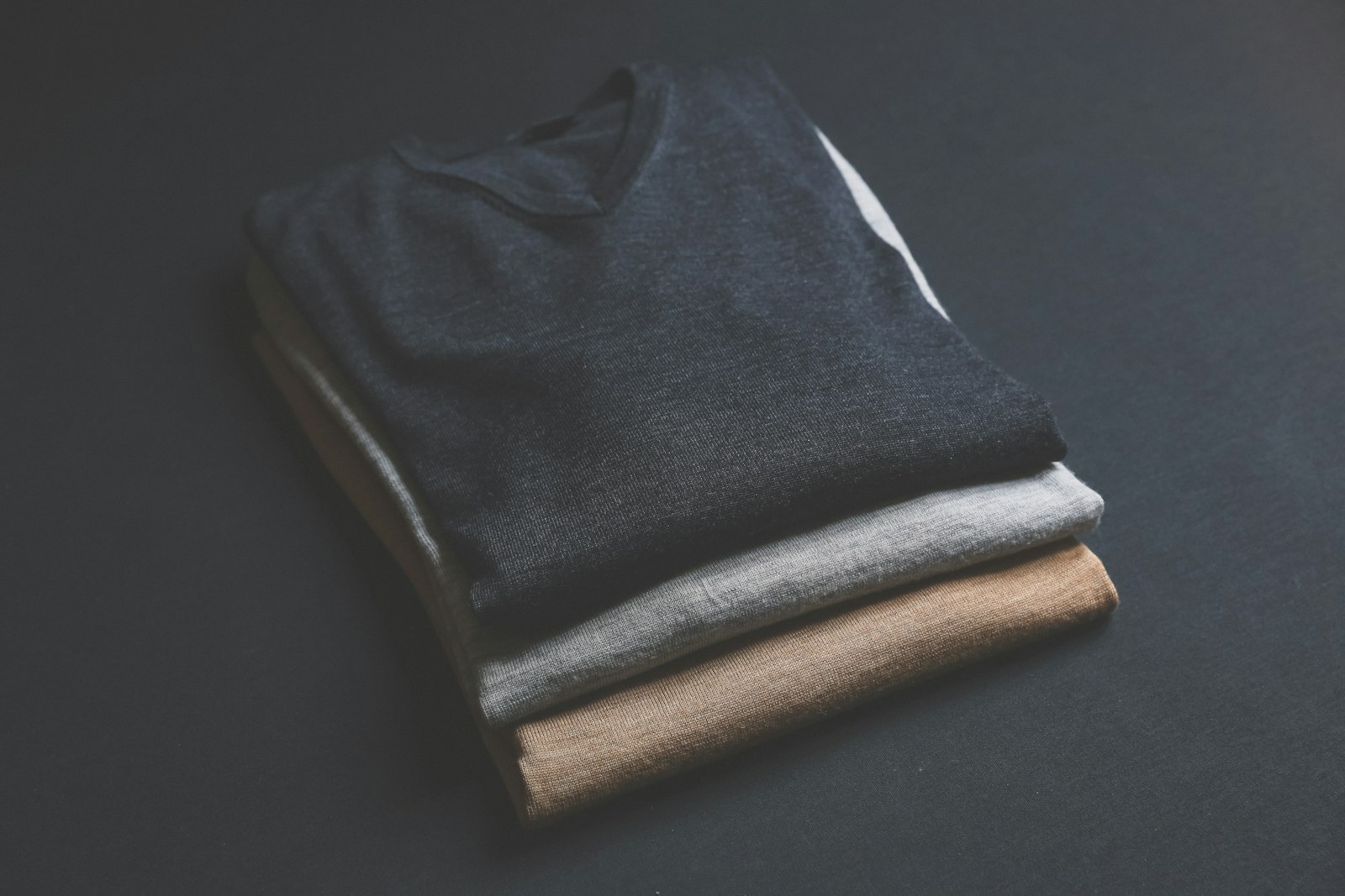 Three folded garments stacked on a black counter