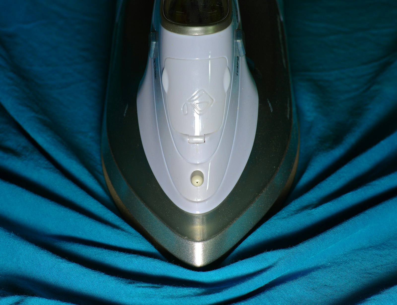 An iron gliding across blue cloth
