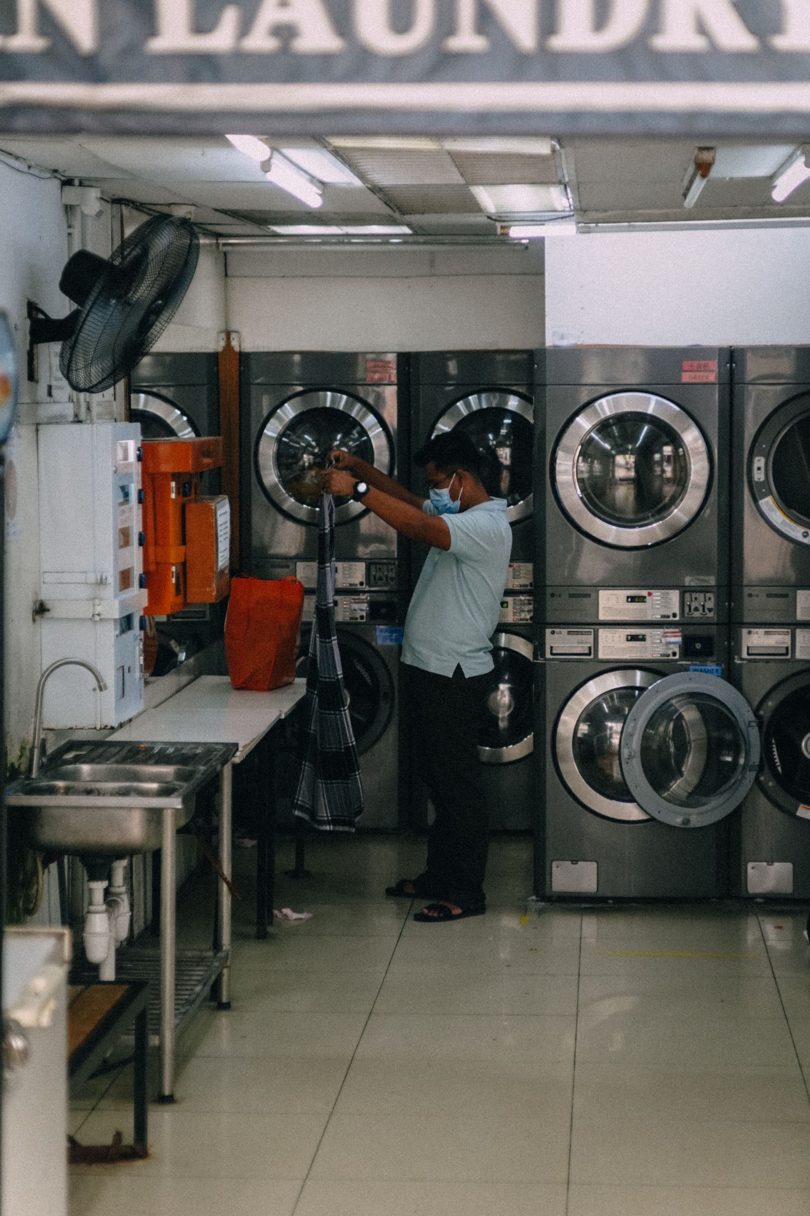Man at work among the garments in a small laundry shop