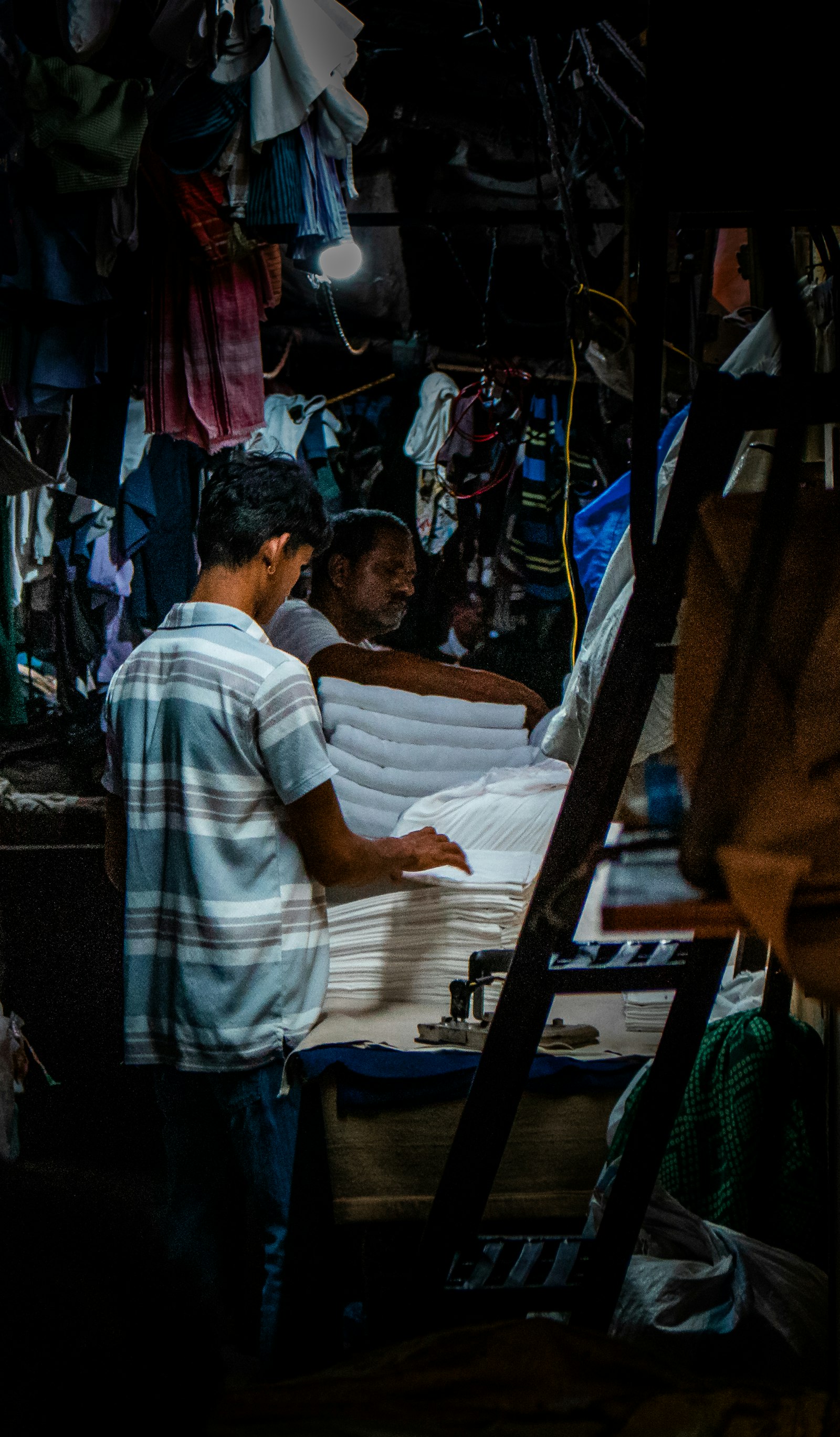 Two staff carrying stacked white linens through the shop