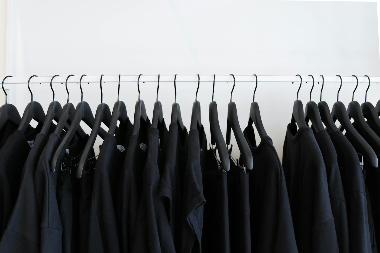 Dark garments hanging on a rail in low light