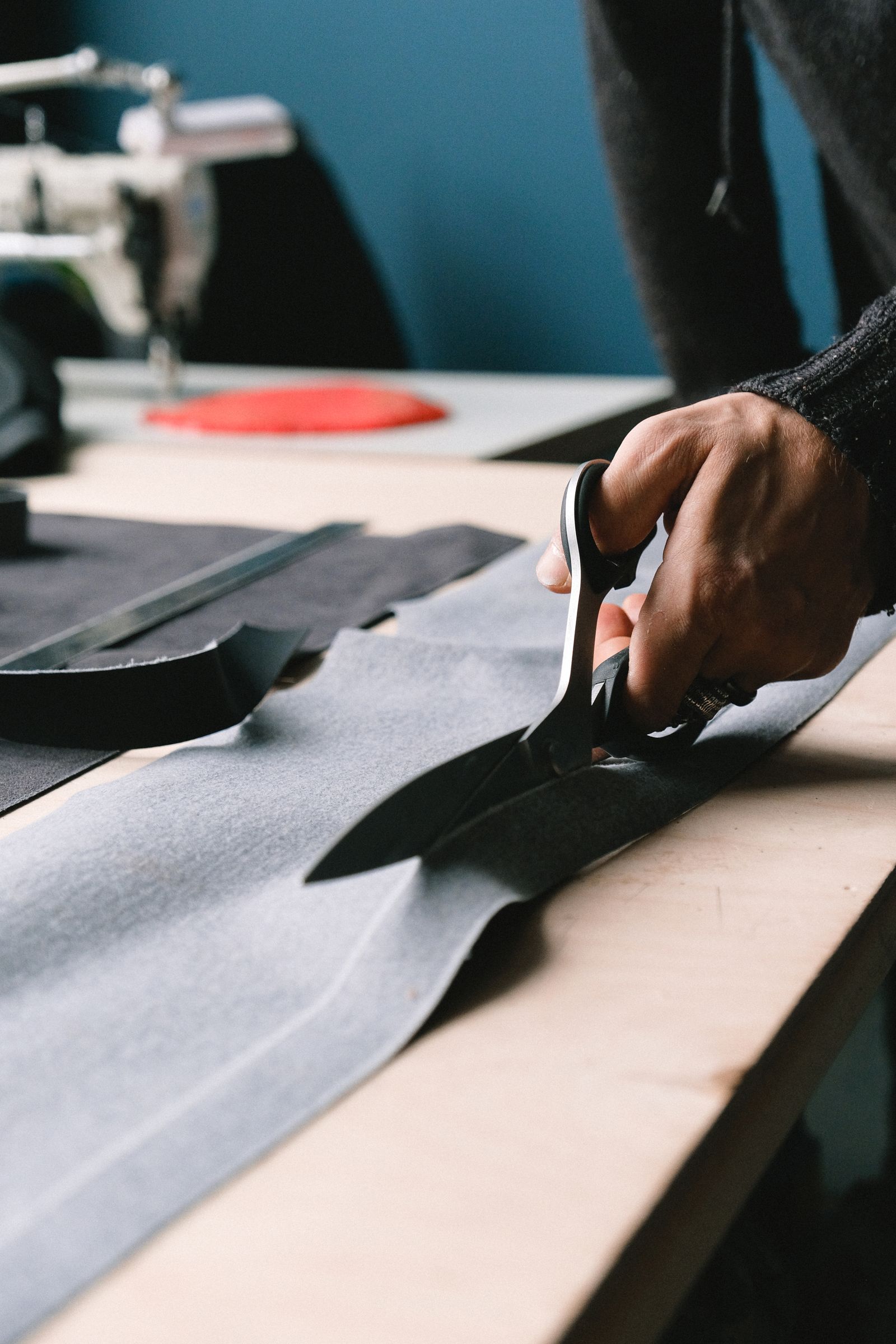 A hand guiding shears through fabric at the tailoring bench