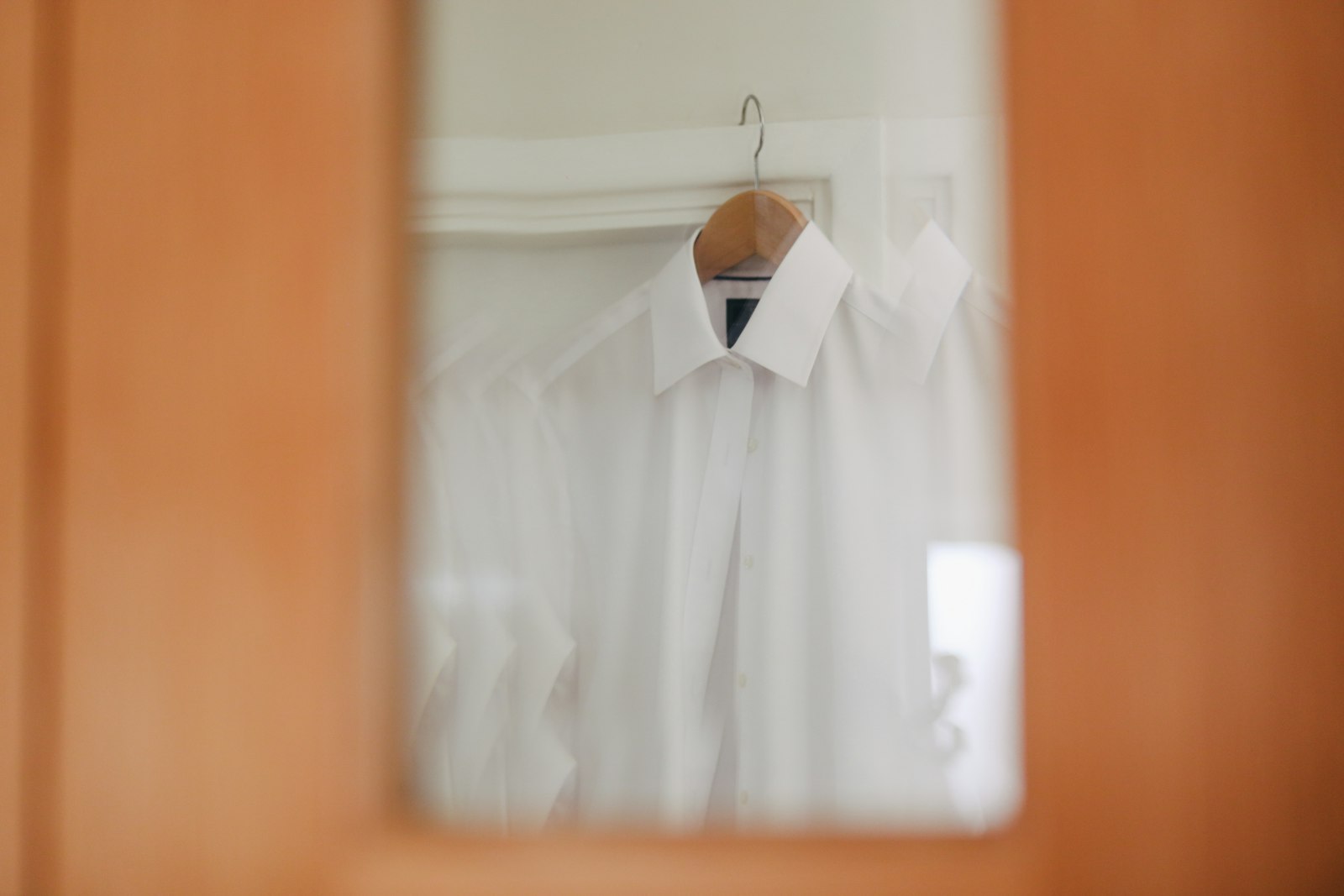 Freshly pressed white dress shirt on a wooden hanger