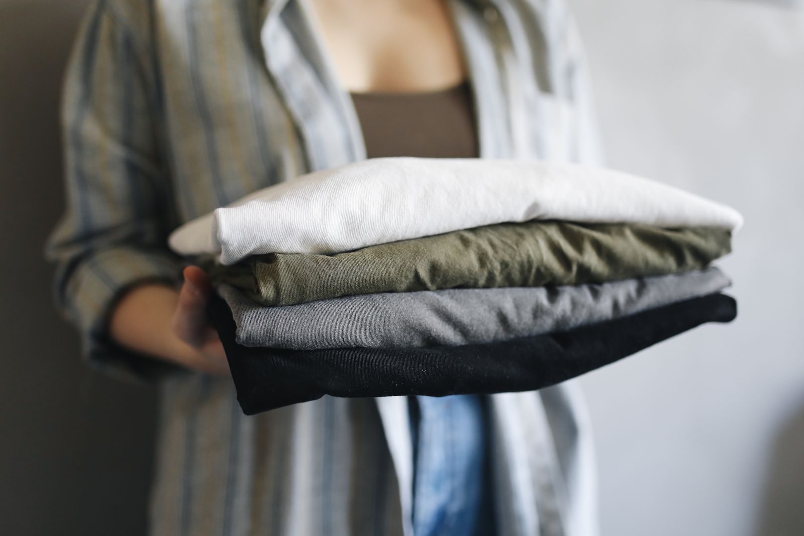 Hands carrying a full stack of folded shirts