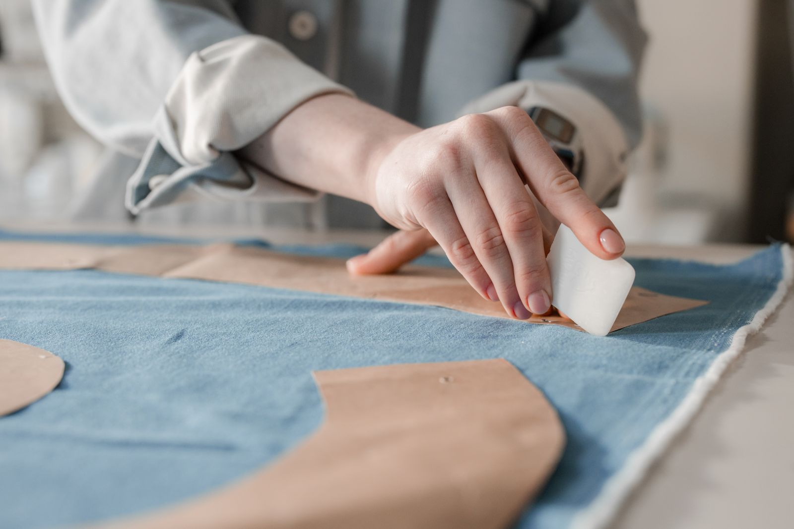 Hands marking a garment with tailor's chalk during inspection